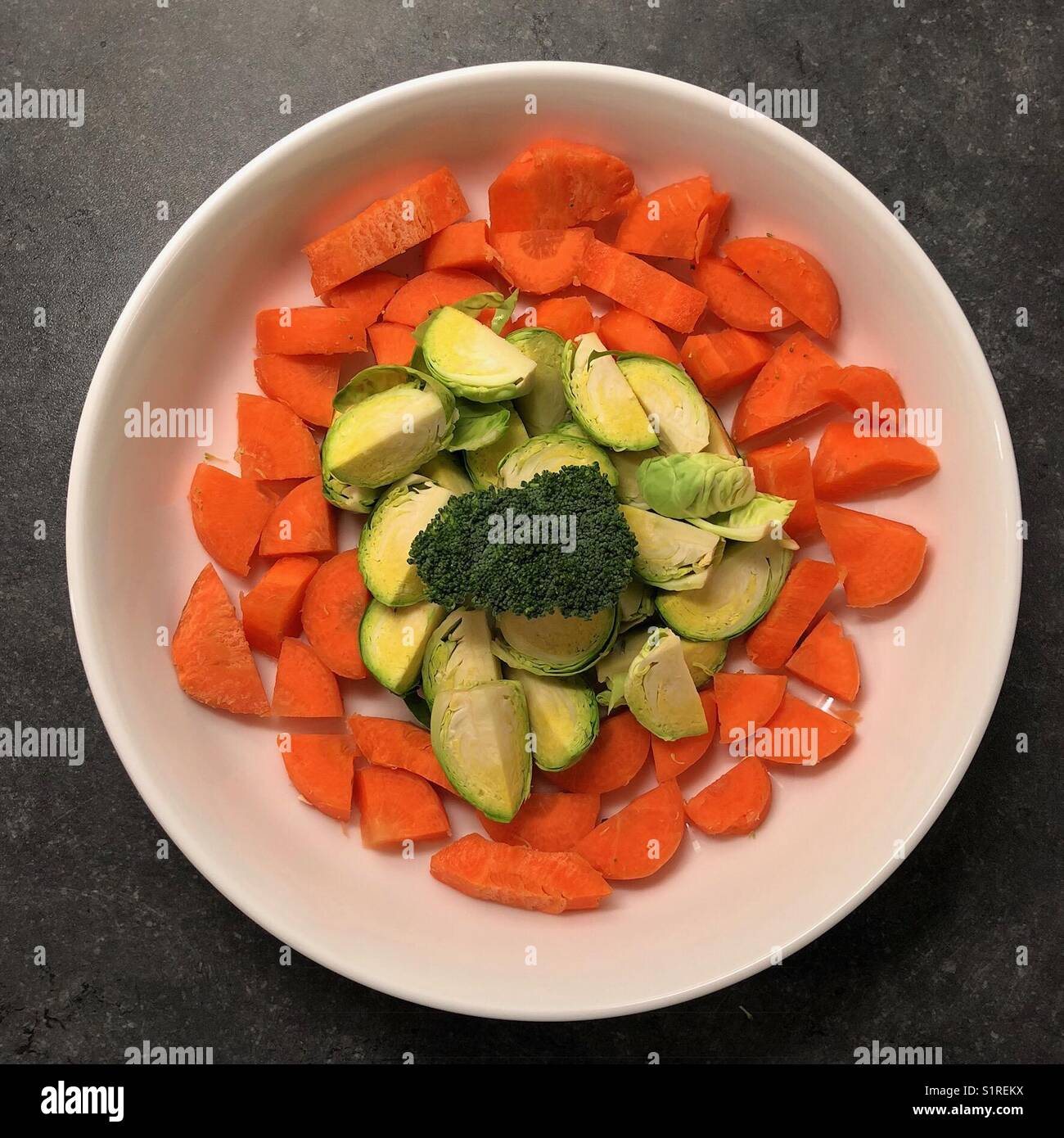 Fresh, chopped vegetables - carrots and greens on a round, white plate Stock Photo