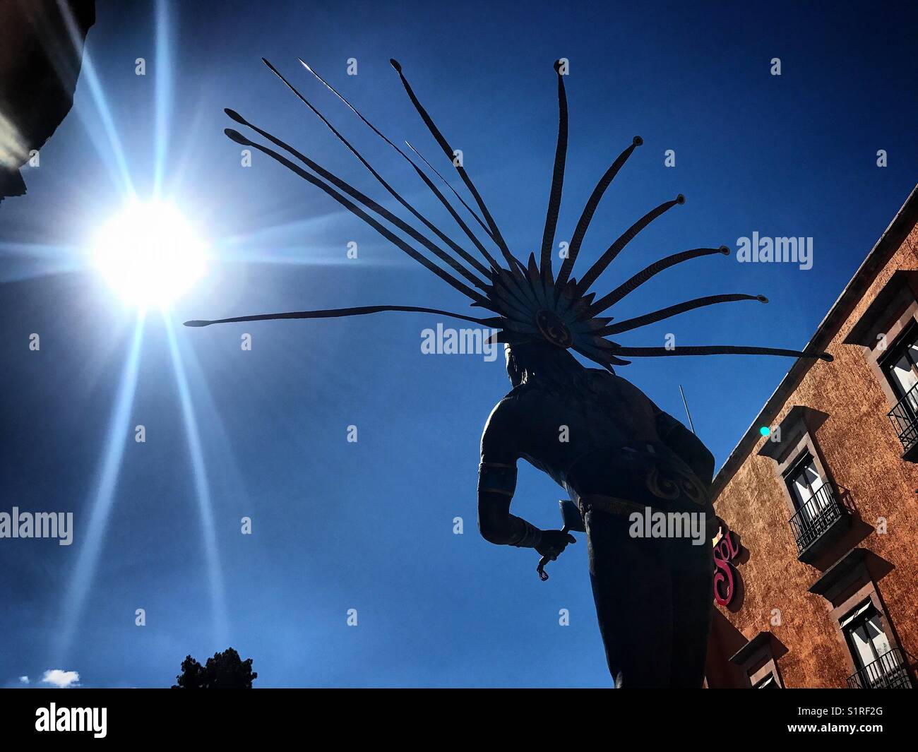 The sun shines in front of the Chichimeca Indian dancer monument  in Queretaro, Mexico - Smartphone Captured Stock Image