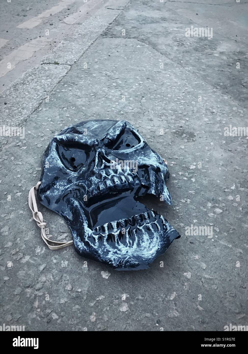 A scary Halloween mask laying in the road, Essex, UK Stock Photo