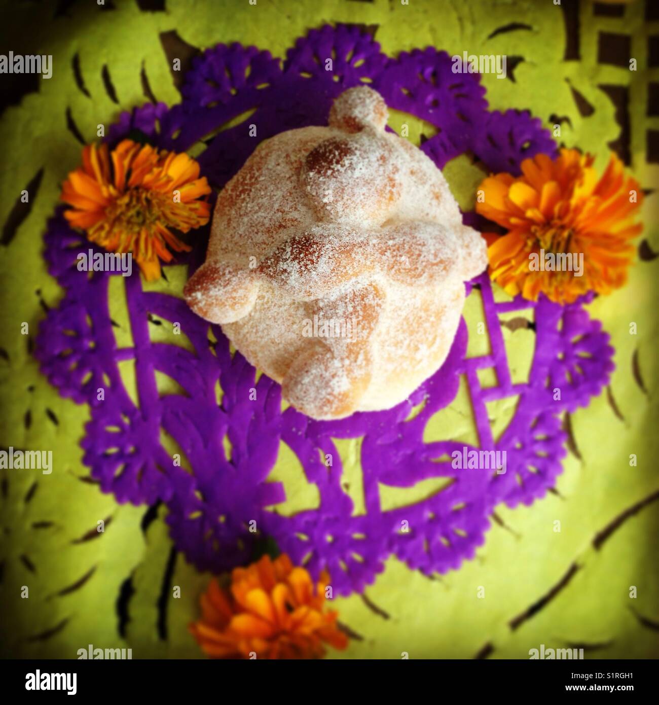 'Pan de Muerto' sweet bread sits on a Day of the Dead altar, along with merigold flowers and paper cut-outs in Mexico City, Tuesday, October 31, 2017. Stock Photo