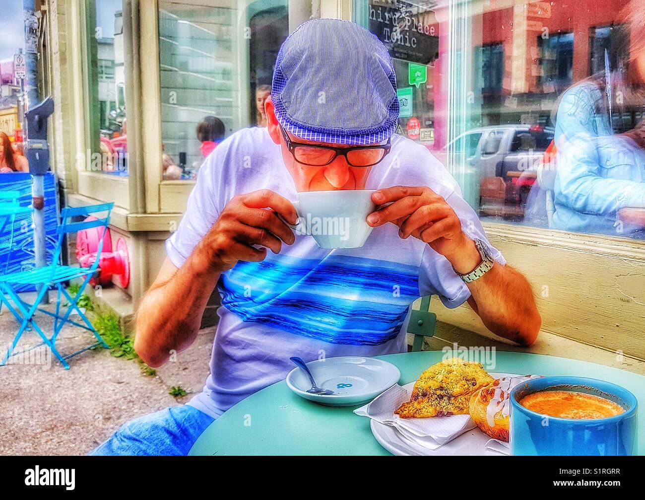 Stylish middle aged man drinking coffee at pavement cafe, St John’s, Newfoundland, Canada - Smartphone Captured Stock Image