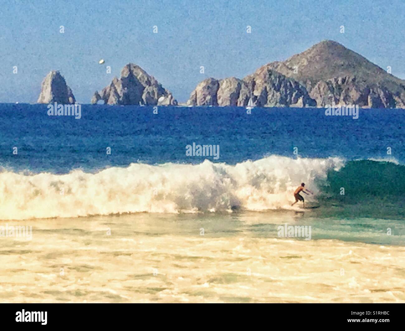 A surfer rides the waves in Cabo San Lucas, Mexico. - Smartphone Captured Stock Image