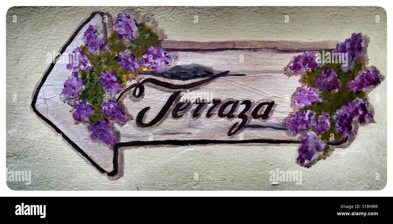 A painted floral directional sign pointing to the terrace. Stock Photo