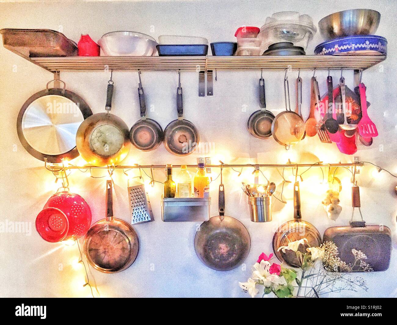 Kitchen utensil rack illuminated with fairy lights. Stock Photo