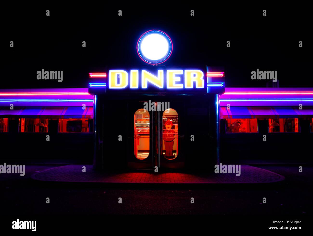 The doorway and bright neon sign at the front of a traditional American Diner at night. - Smartphone Captured Stock Image