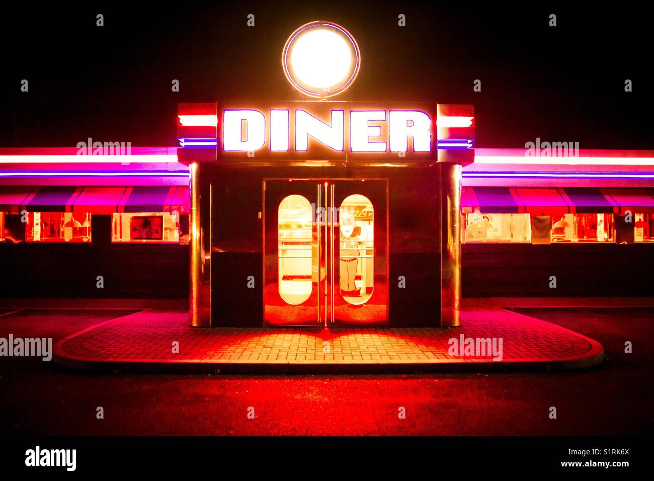 The neon strip lights and fluorescent lighting outside a traditional American Diner with the doorway brightly lit with colourful lights. - Smartphone Captured Stock Image