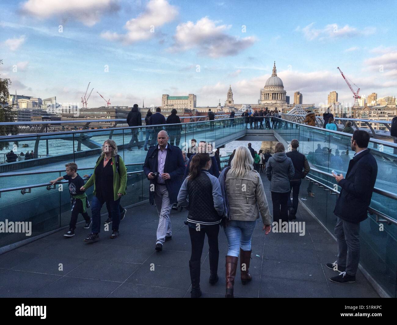People walking over Millennium Bridge, designed by Norman Foster. St Paul's Cathedral is seen in the distance. Photo taken on November 3 2017 - Smartphone Captured Stock Image