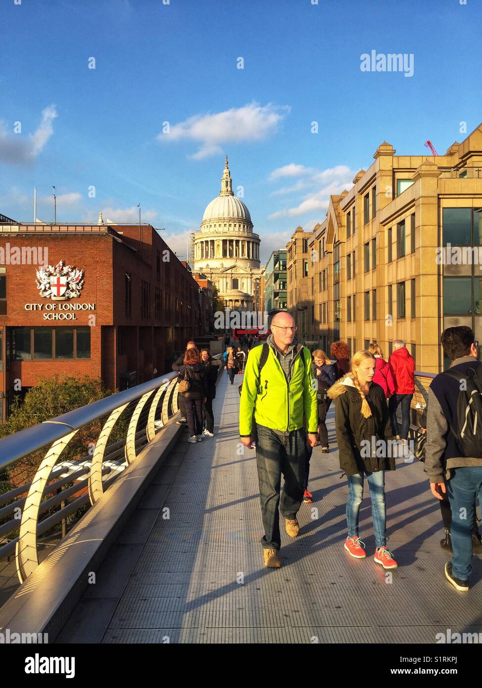 People walk over Millennium Bridge, designed by Norman Foster. St Paul's Cathedral is seen in the distance. Photo taken on November 3 2017 - Smartphone Captured Stock Image