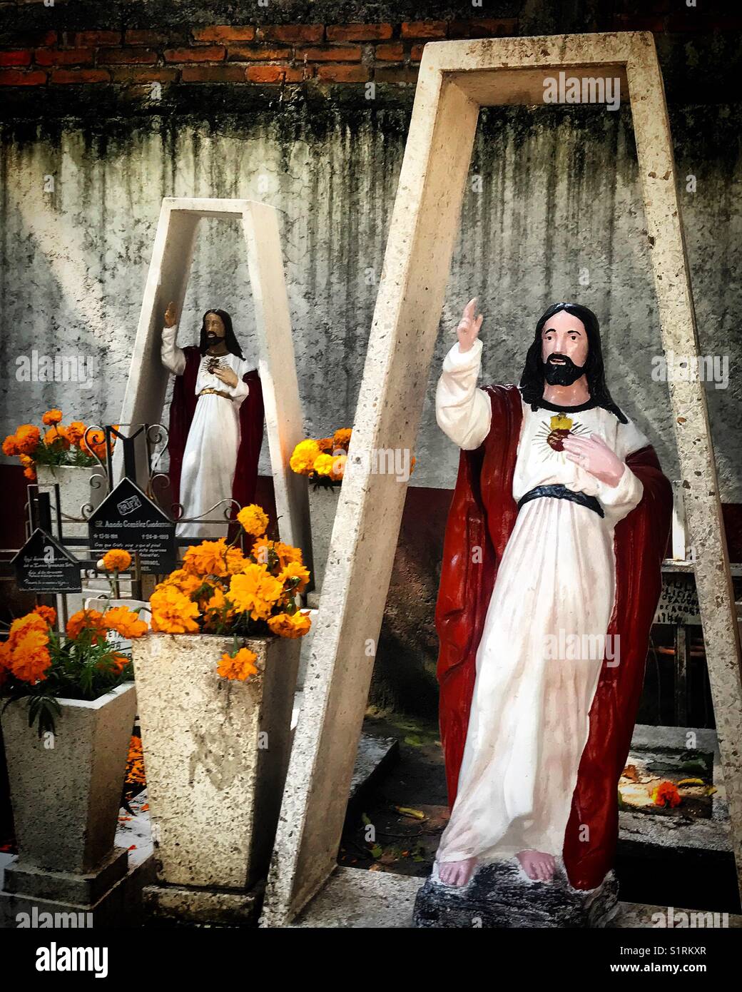 Marigold flowers and images of the Sacred Heart of Jesus decorate  tombs during Day of the Dead in Mexico City, Mexico. Stock Photo