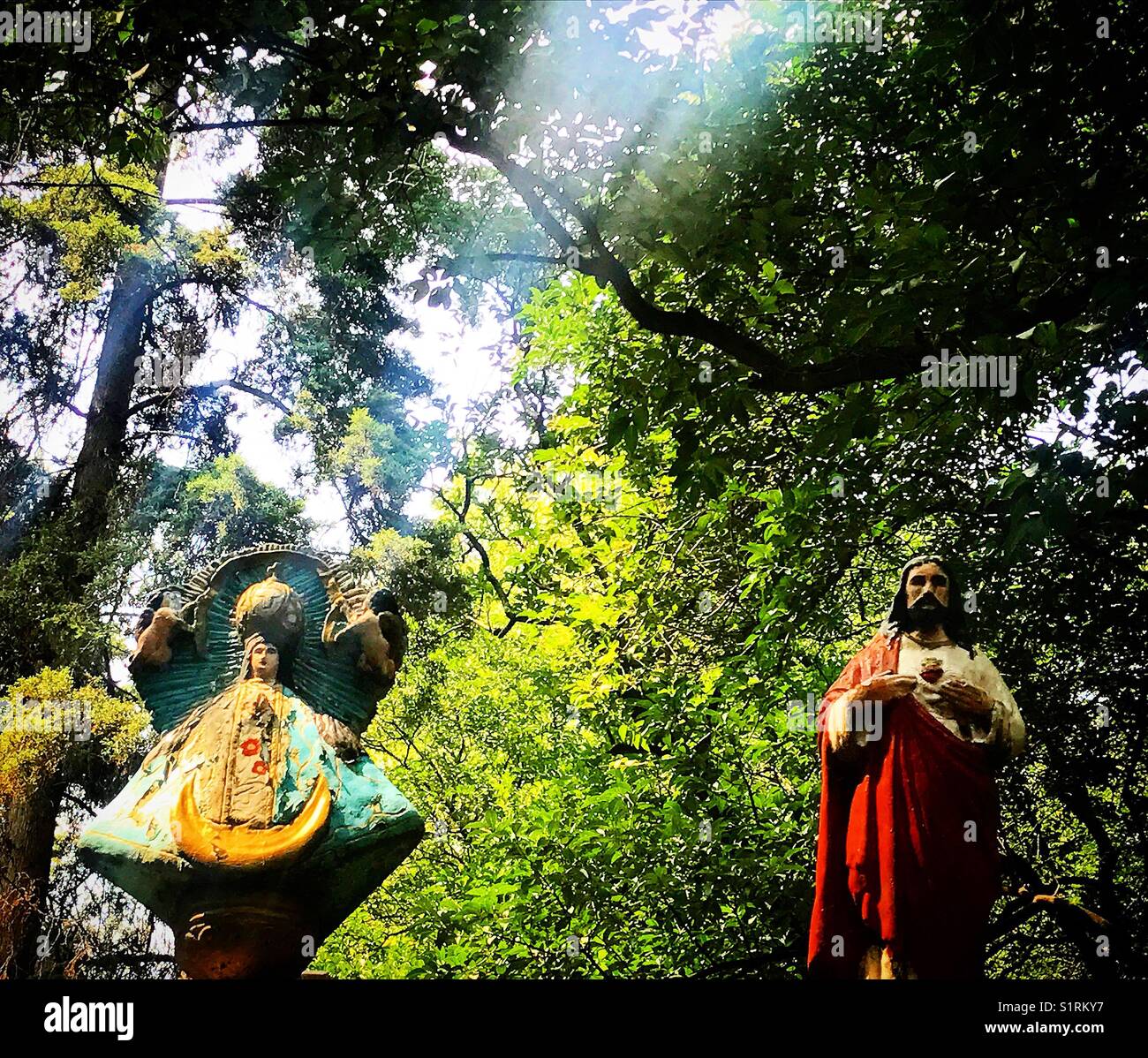 A ray of sunlight illuminates an image of the Virgin of San Juan de los Lagos close to a Sacred Heart of Jesus during Day of the Dead in Mexico City, Mexico. - Smartphone Captured Stock Image