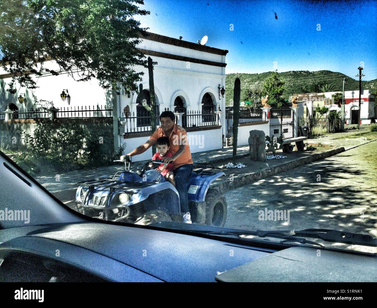Father and son riding a dune buggy through El Triunfo, an old abandoned mining town on Baja California, Mexico. - Smartphone Captured Stock Image