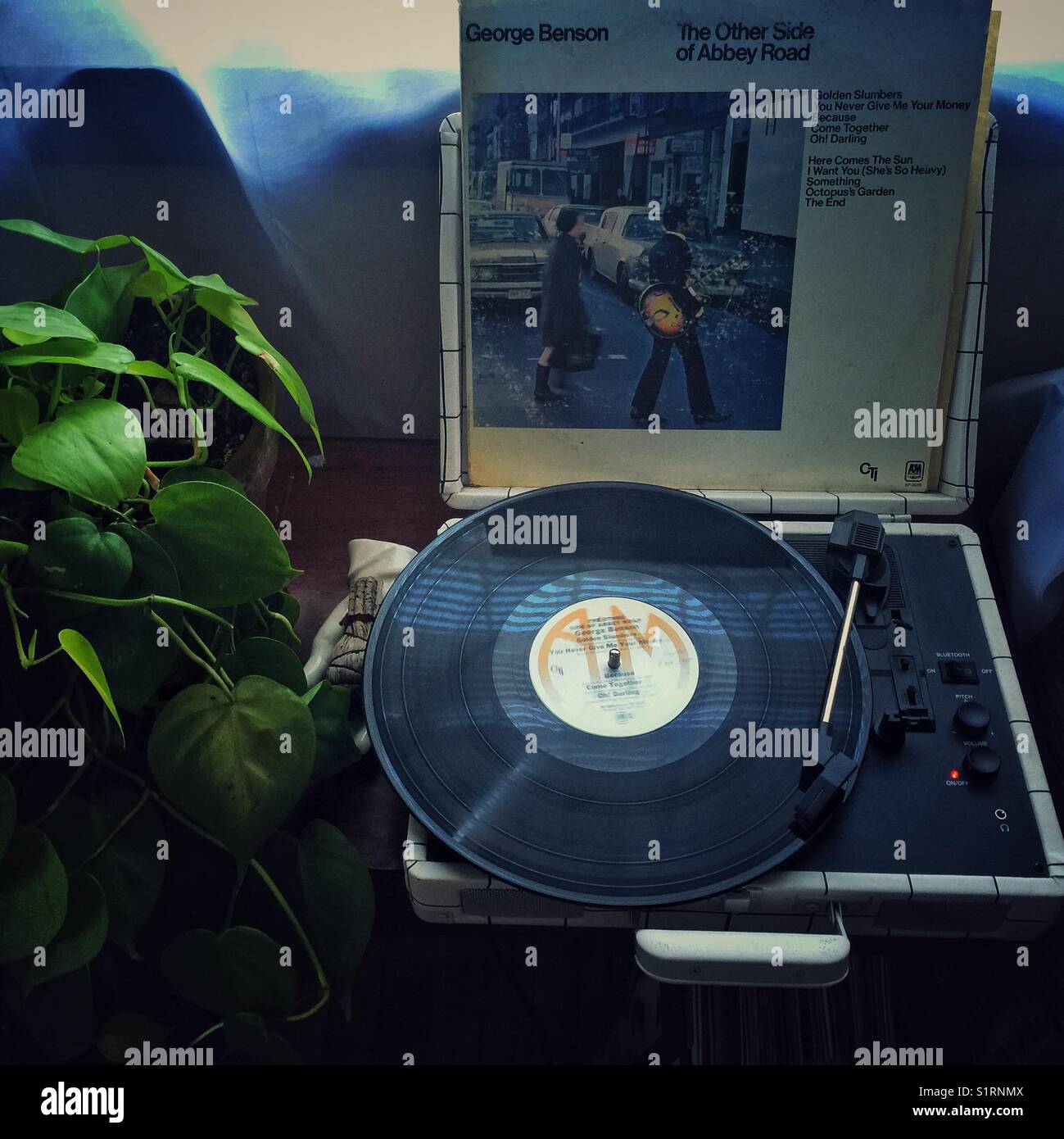 Vintage George Benson's record The Other Side of Abbey Road playing on compact record player - Smartphone Captured Stock Image