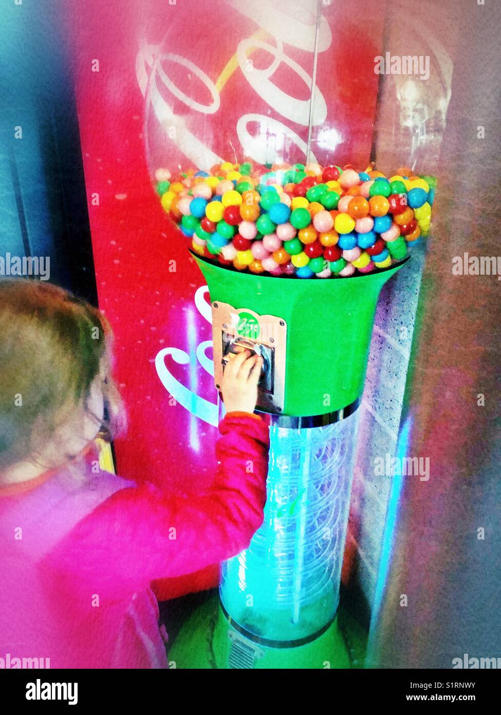 Little girl putting money in a large gum ball machine Stock Photo