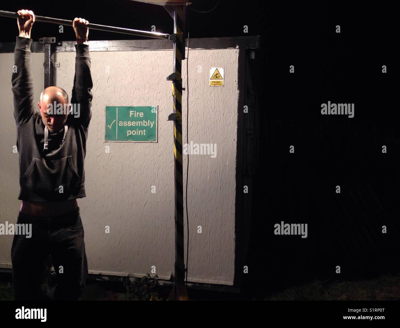 Man hanging from a bar at night - Smartphone Captured Stock Image