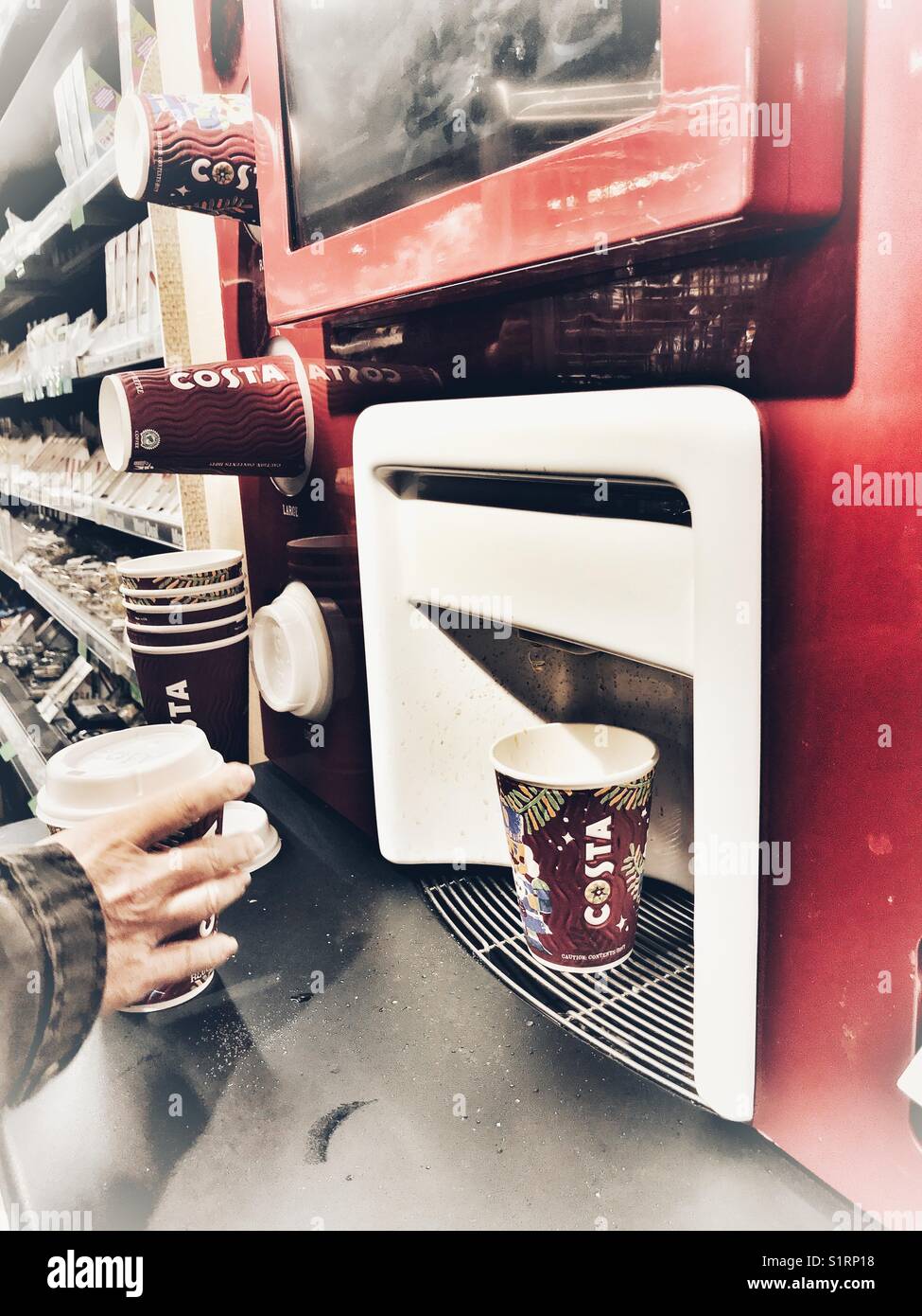 Woman using a Costa coffee self service vending machine in a supermarket on a university campus. - Smartphone Captured Stock Image