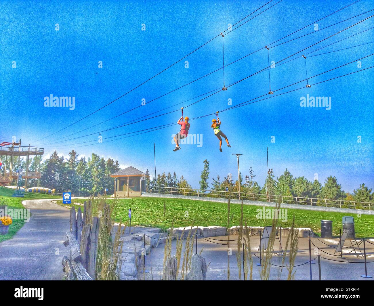 A couple zip lining at Blue Mountain Village, Collingwood, Ontario, Canada. - Smartphone Captured Stock Image