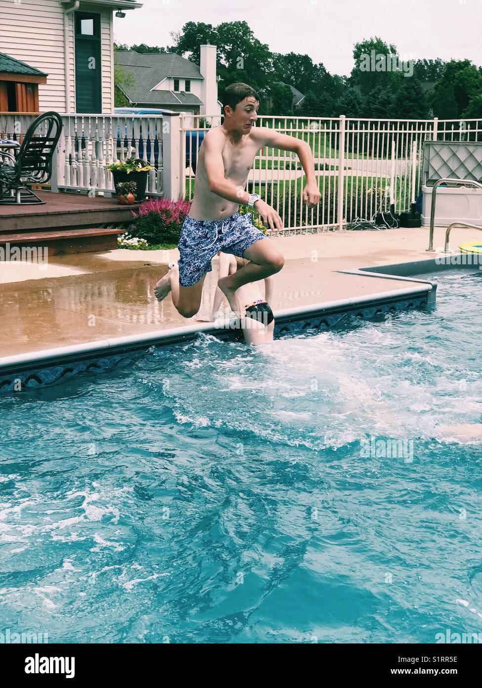 Teen boy jumping in pool Stock Photo