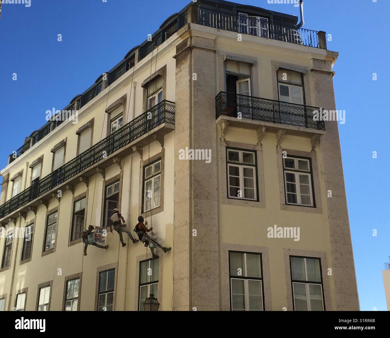 Three men painting side of building Stock Photo