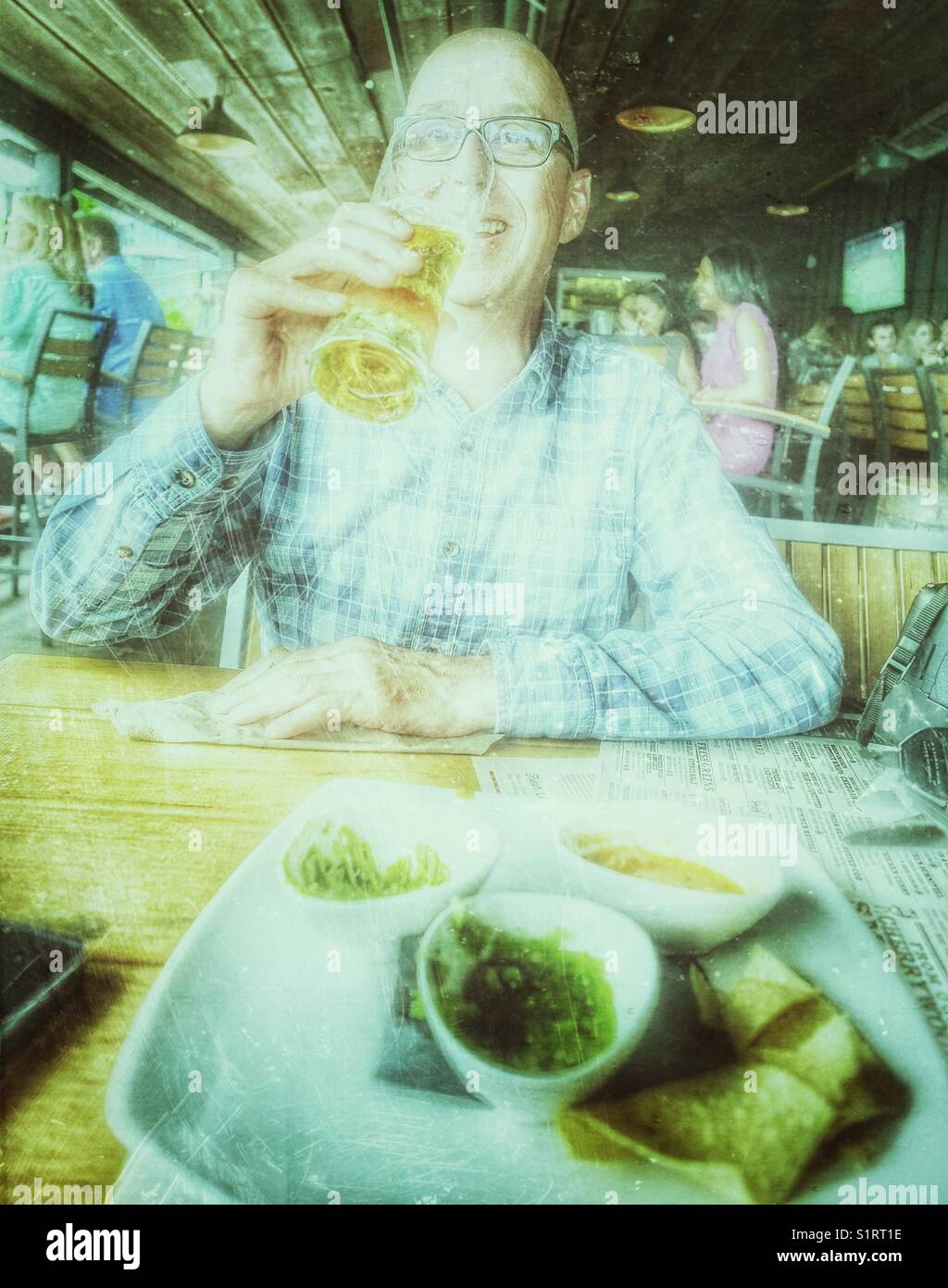 Middle aged smiling man drinking beer in restaurant, Toronto, Ontario, Canada - Smartphone Captured Stock Image