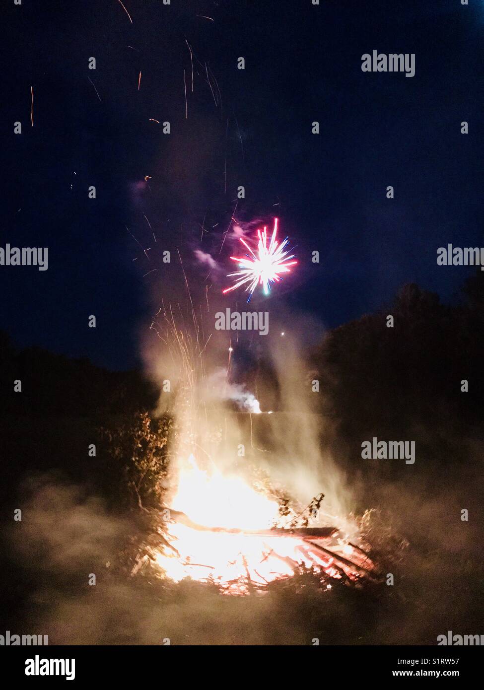 Fireworks exploding above a campfire Stock Photo