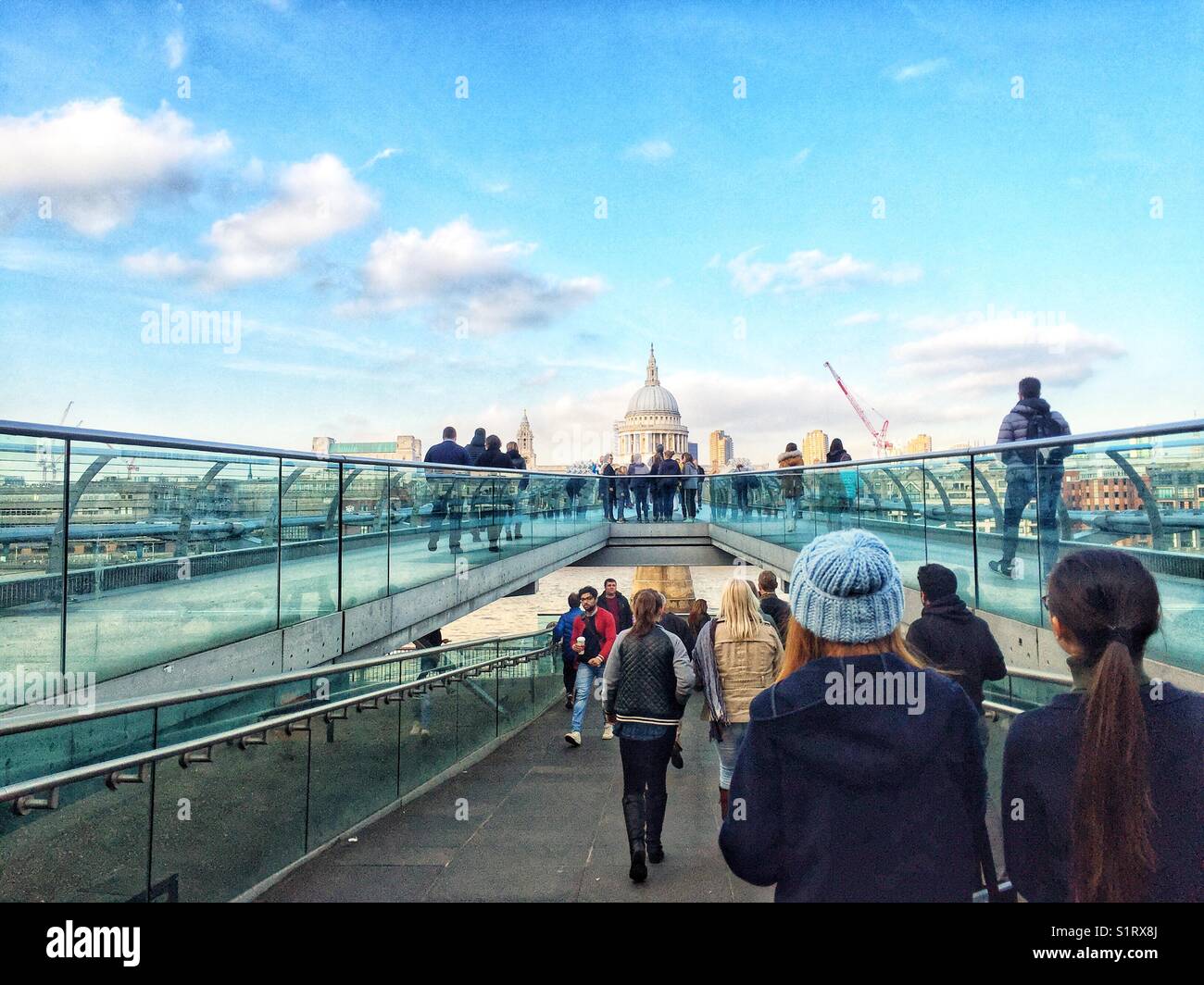 People walking over Millennium Bridge, designed by Norman Foster. St Paul's Cathedral is seen in the distance. Photo taken on November 3 2017 - Smartphone Captured Stock Image