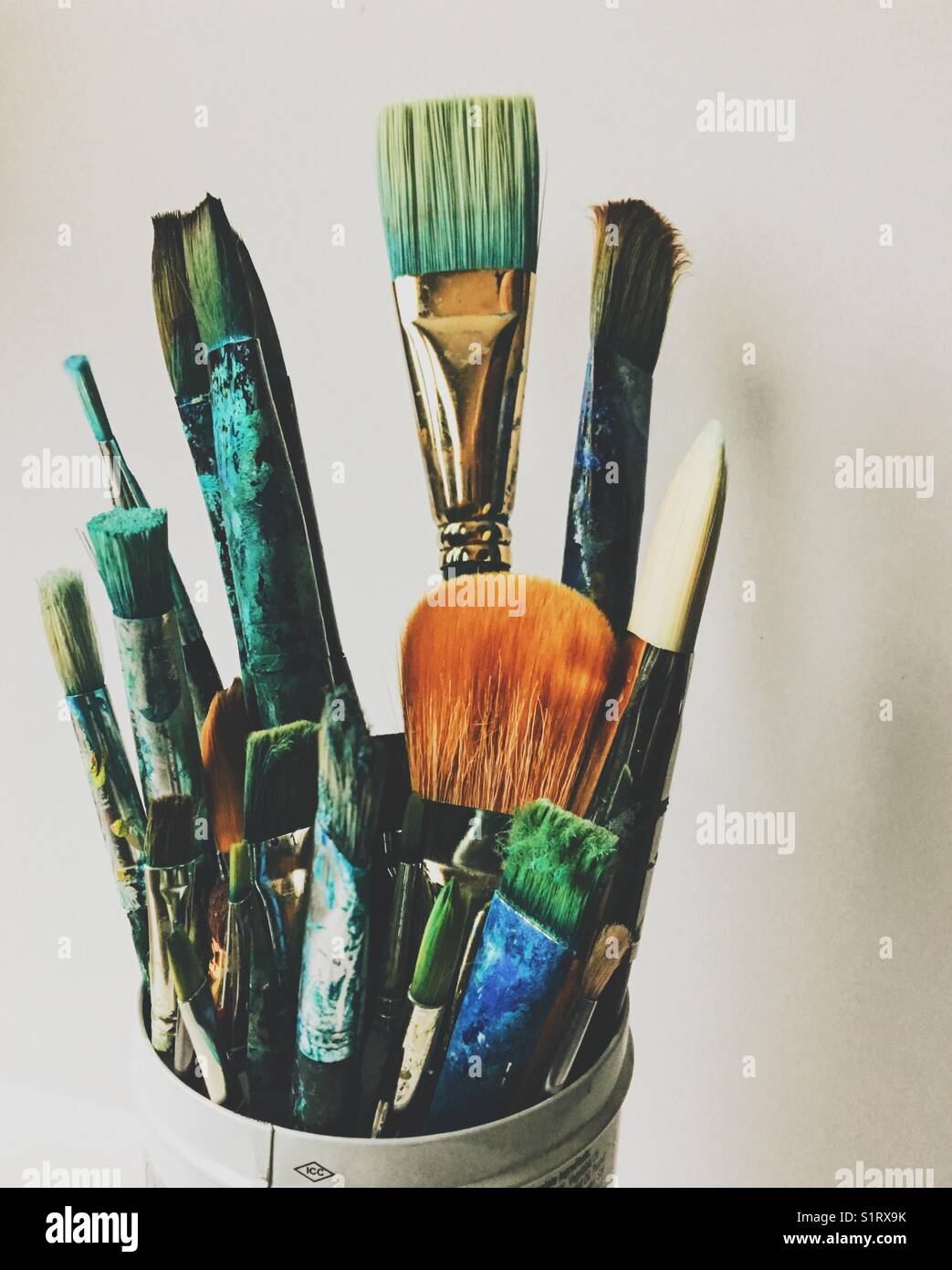 Close up of an assortment of paintbrushes in a white tin can with white background. - Smartphone Captured Stock Image