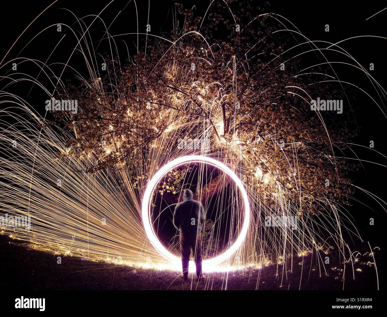 Steel wool spinning under apple tree Stock Photo