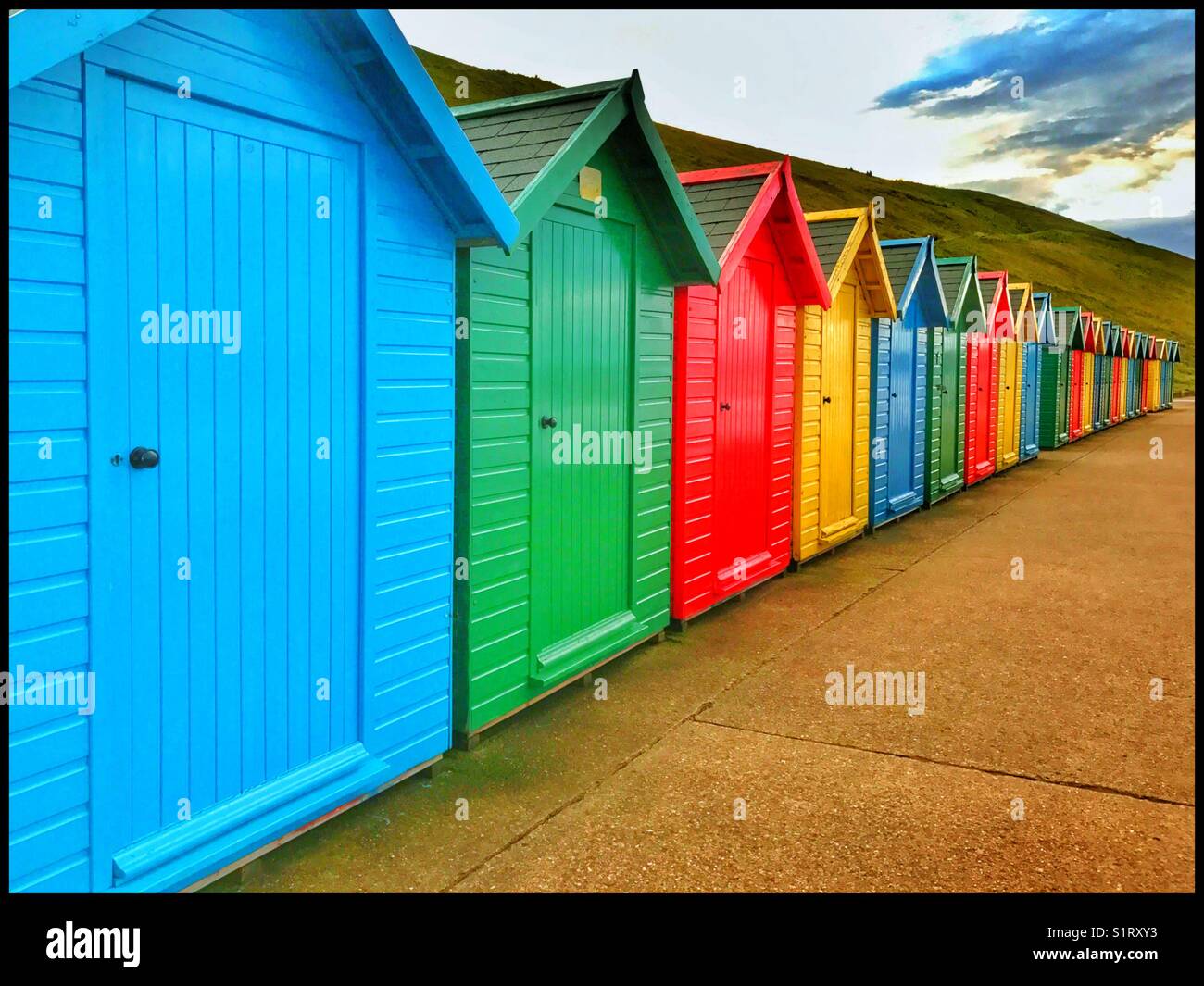 A row of colourful beach huts along the shore line at Whitby, Yorkshire, England. All the huts are closed and everybody has gone. Photo Credit - © COLIN HOSKINS. - Smartphone Captured Stock Image