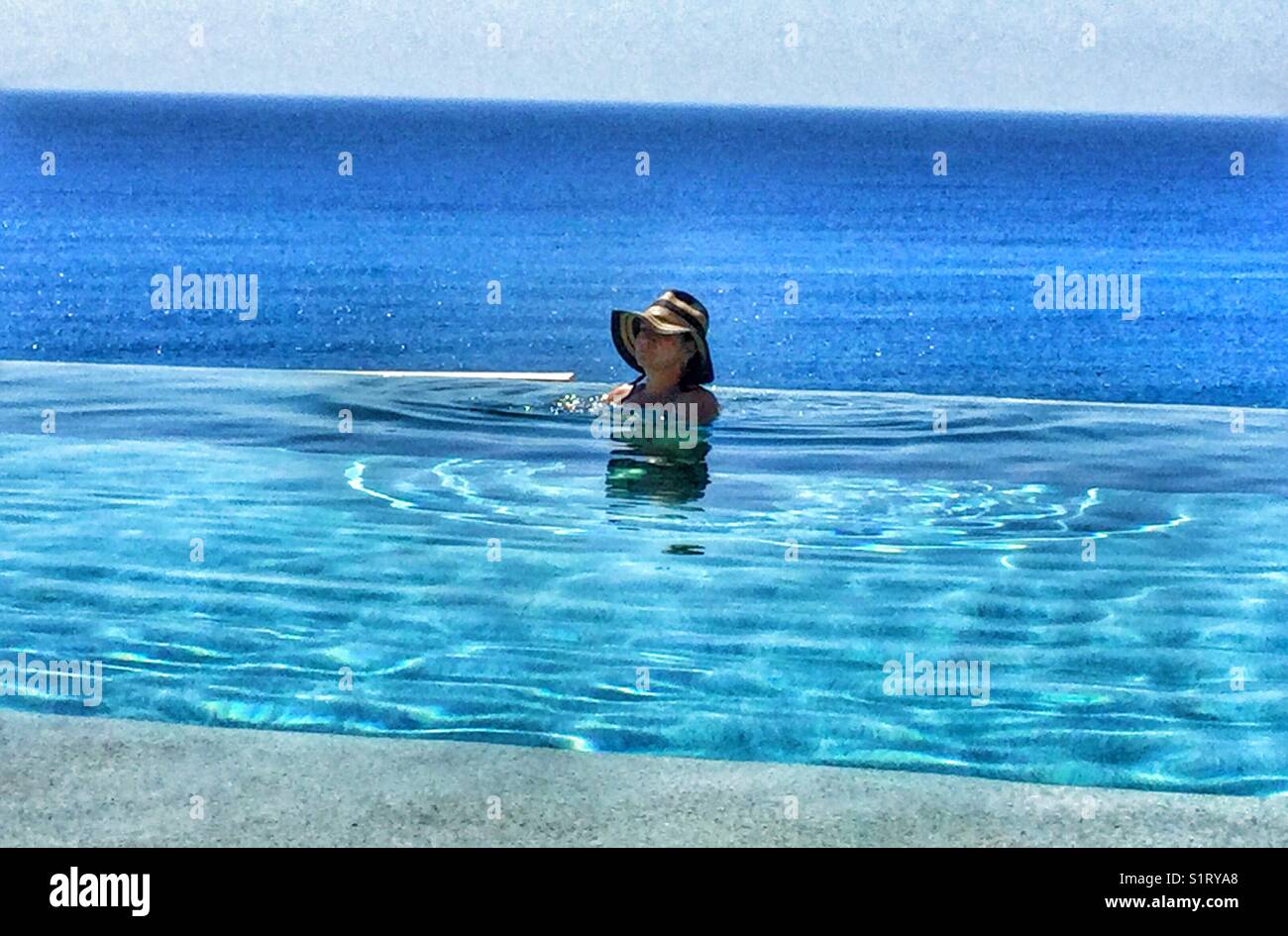 A woman cooling off in an infinity pool. - Smartphone Captured Stock Image
