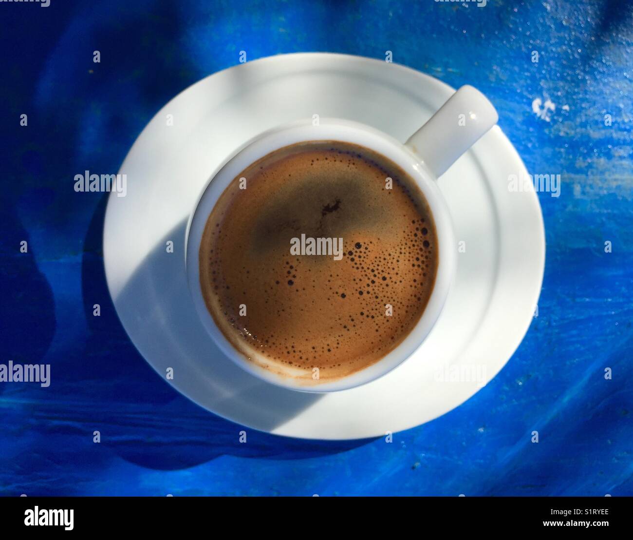 Cup of strong Turkish coffee in a white cup on a blue wooden table - Smartphone Captured Stock Image