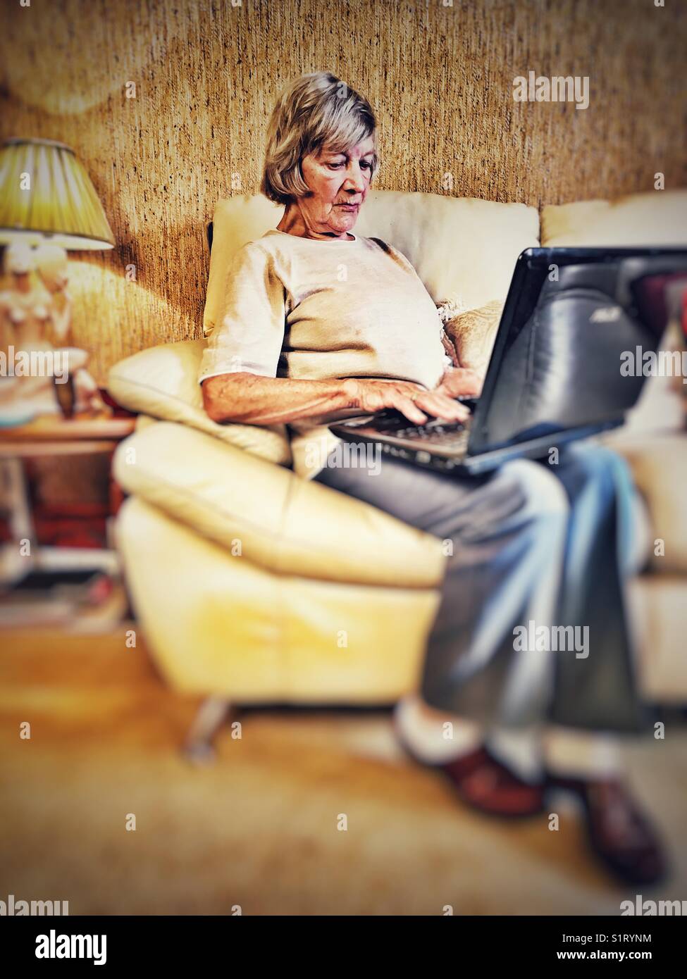 Elderly woman using a laptop computer to access the internet - Smartphone Captured Stock Image