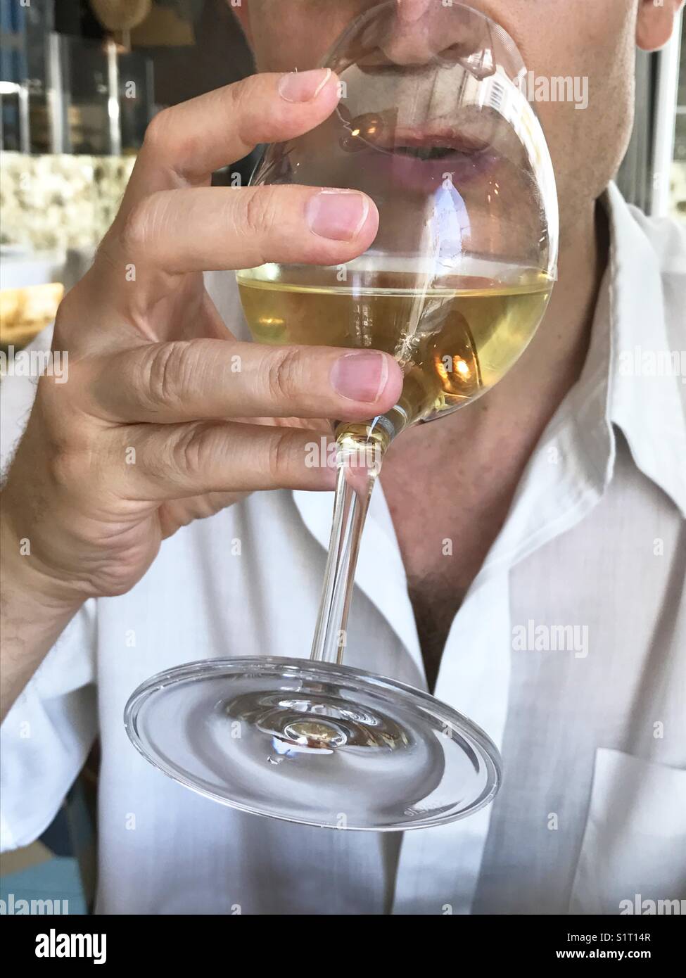Man drinking a glass of white wine. Close view. - Smartphone Captured Stock Image