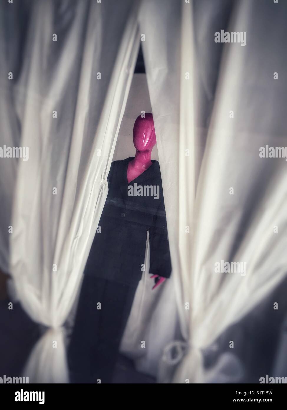 Hot pink mannequin wearing black suit in thrift store window Stock Photo