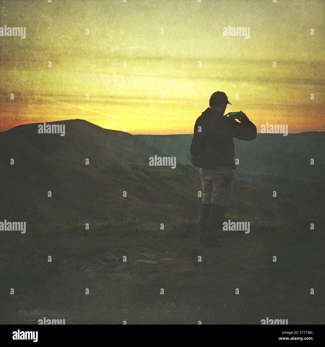 Hiker taking a photo with his phone at the top of Mam Tor, Peak District, UK - Smartphone Captured Stock Image