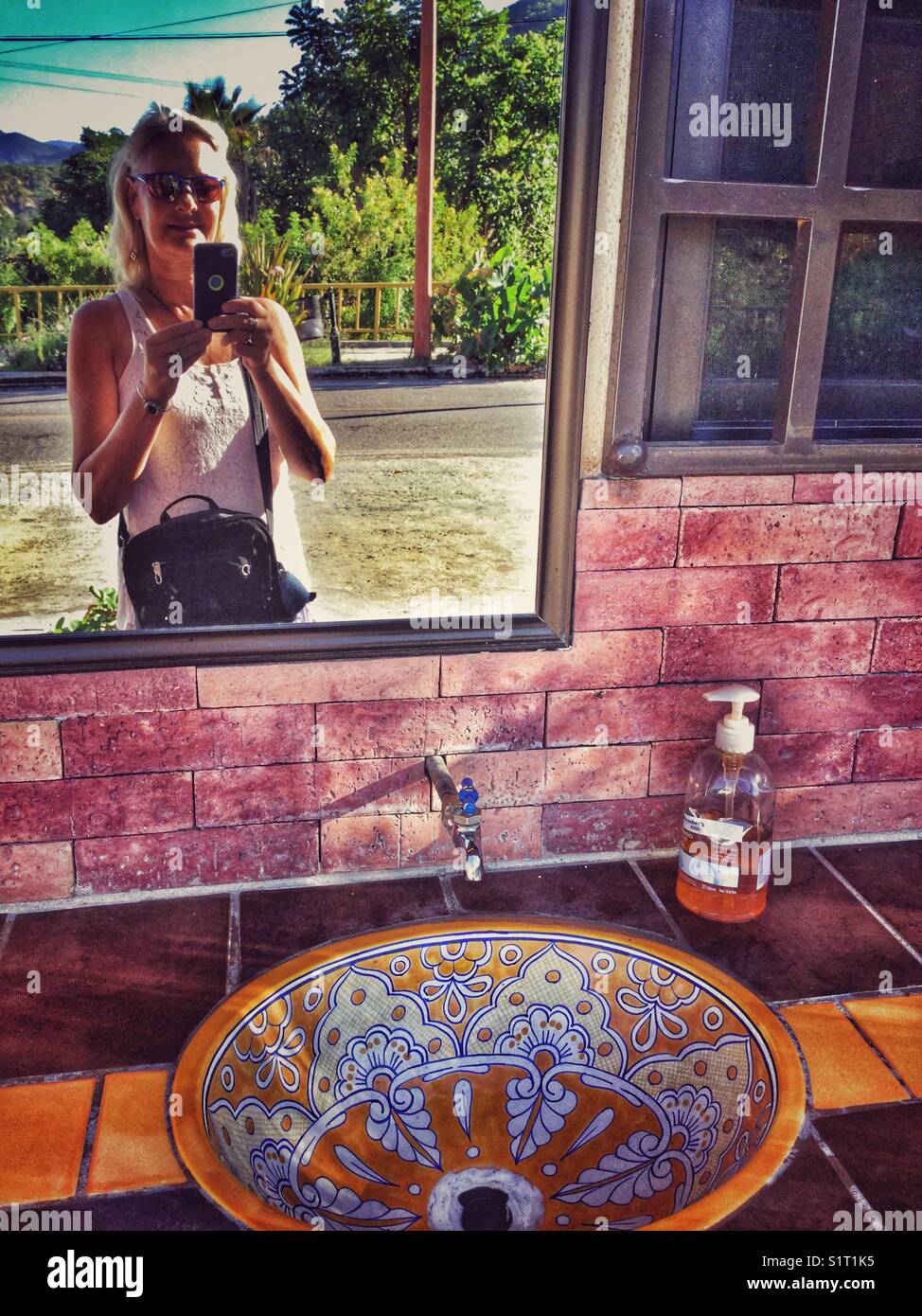 A woman takes a selfie into a mirror at a roadside restroom in Mexico. Stock Photo