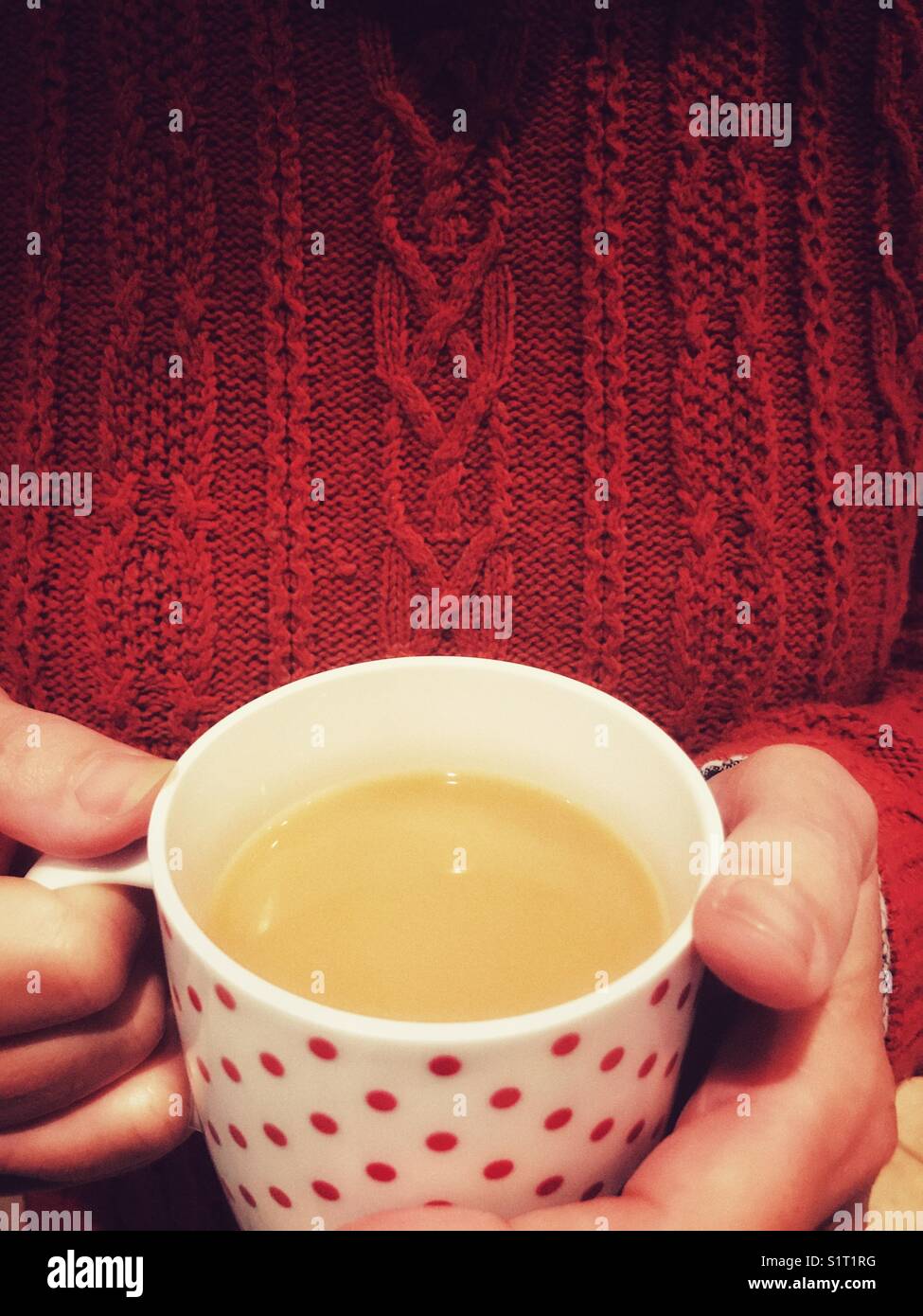 Woman wearing a knitted sweater holding a mug of tea, close-up. - Smartphone Captured Stock Image