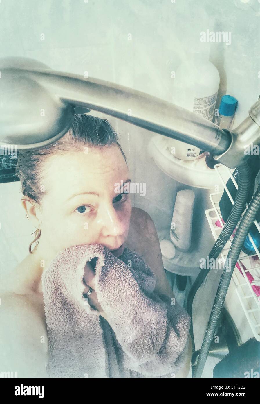 Looking down at woman in steamy shower stall holding towel Stock Photo