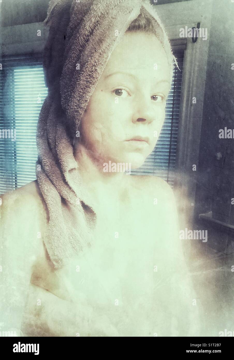 Portrait of a woman with towel on head in a steamy washroom after having a shower Stock Photo