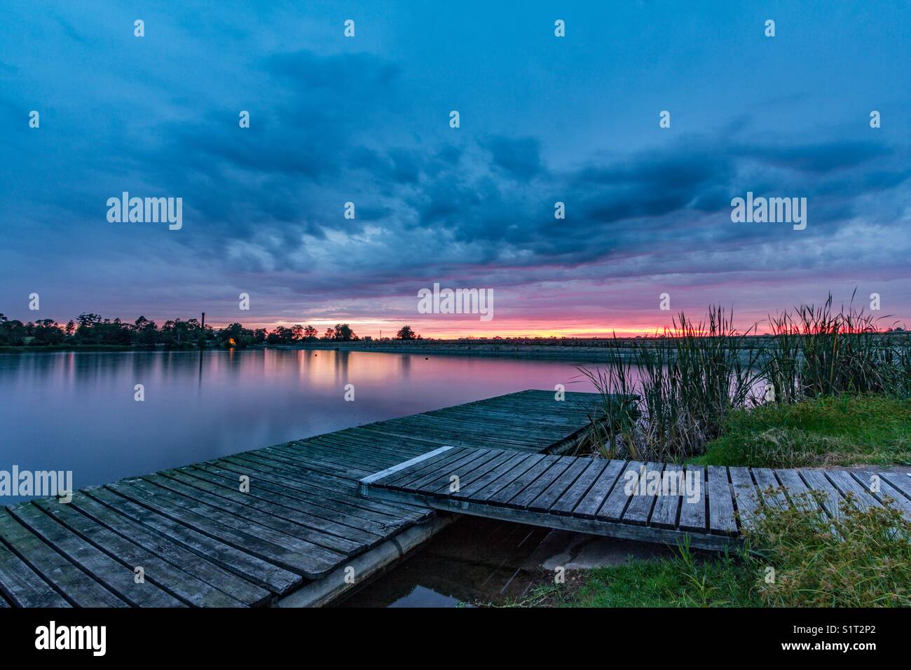 Old timber jetty on lake with sunrise reflected in water - Smartphone Captured Stock Image