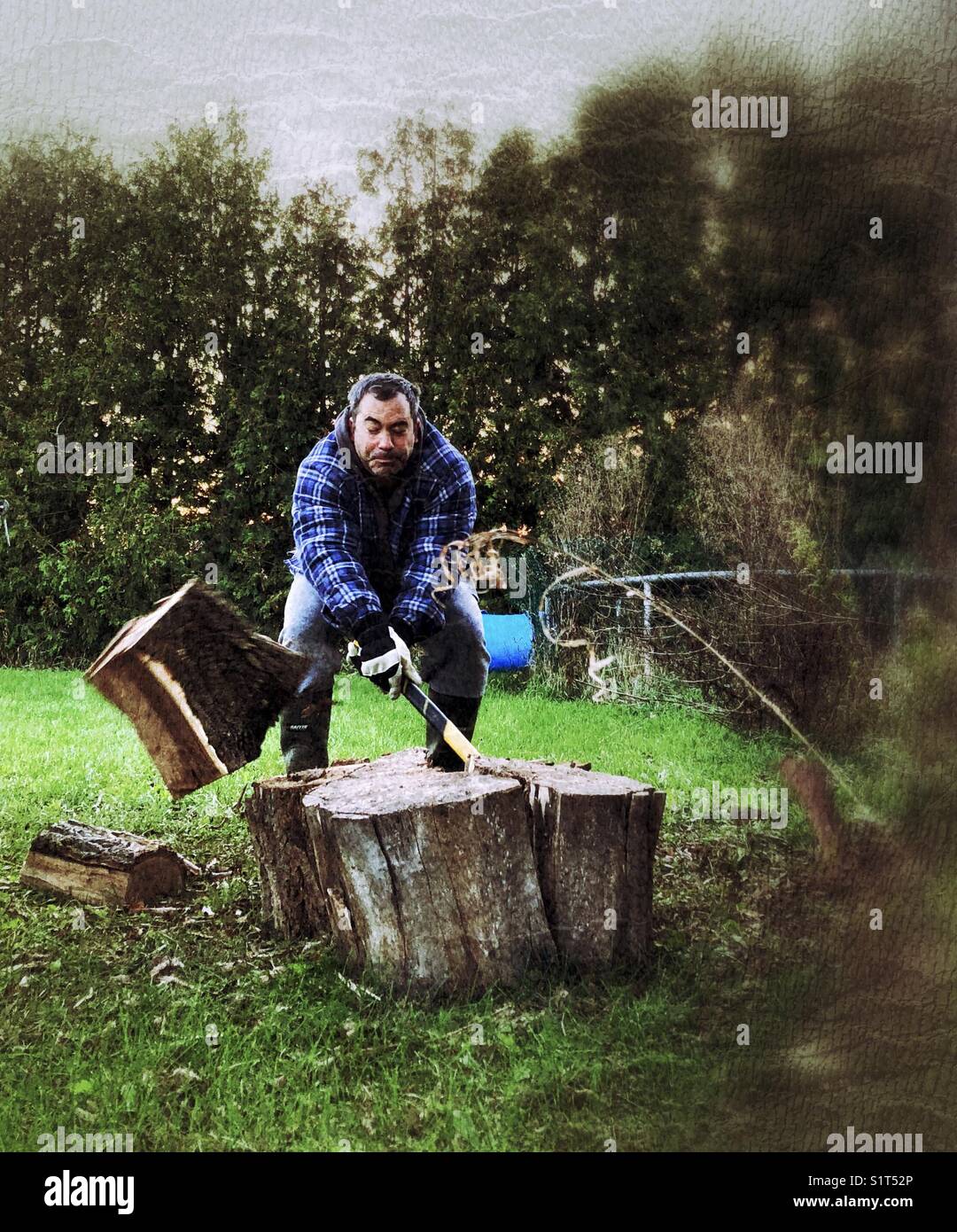 Action shot of man chopping wood with piece of wood flying off to the side - Smartphone Captured Stock Image