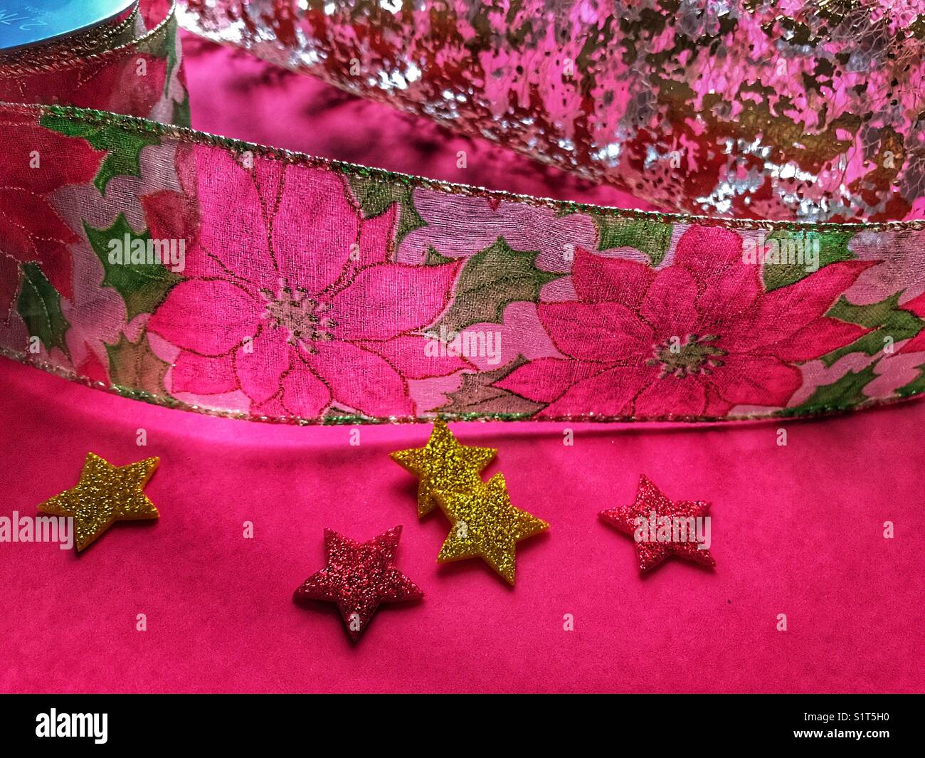 Christmas theme. Poinsettia wire ribbon, gold lace paper and stars on red. - Smartphone Captured Stock Image