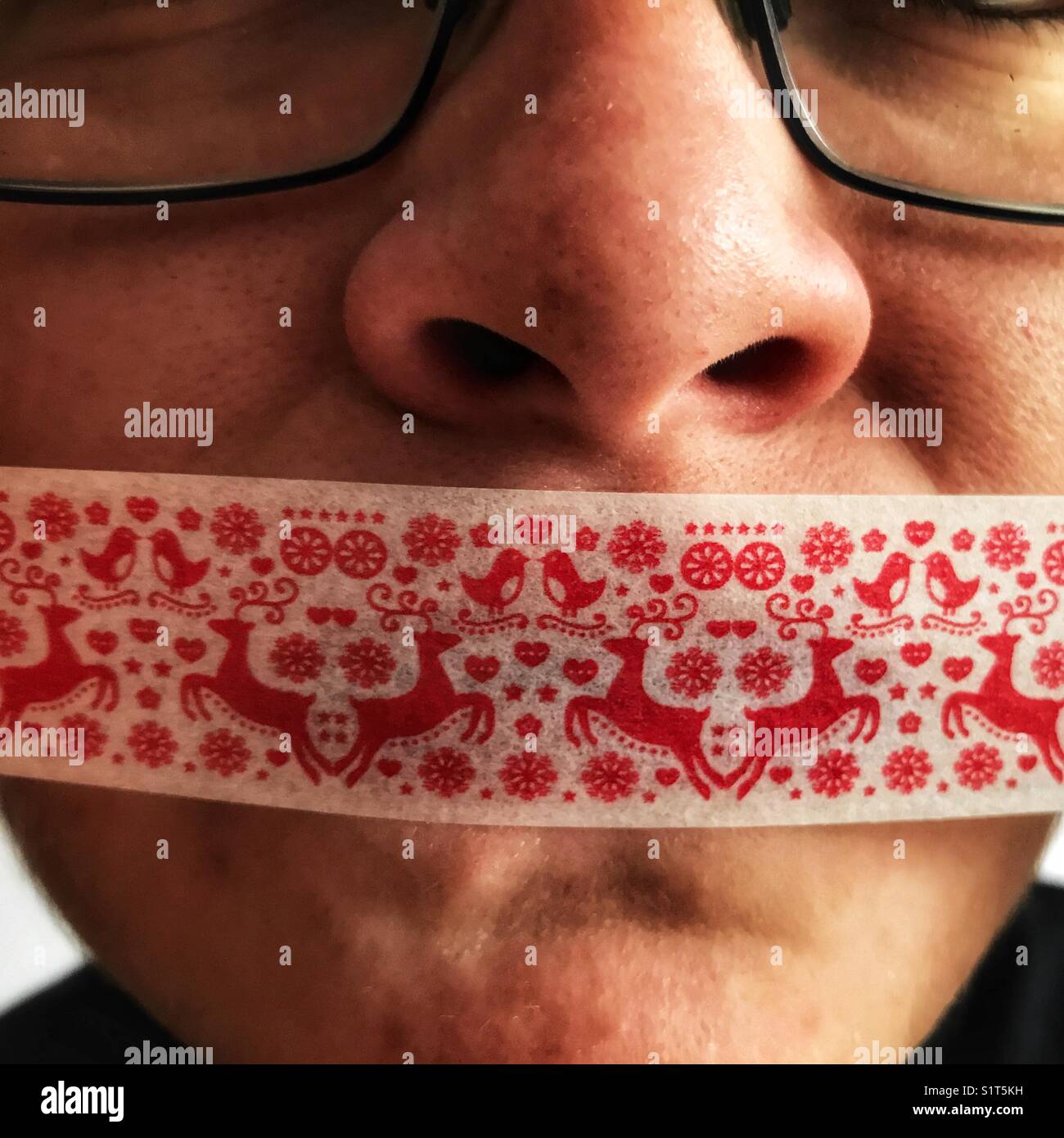 Young woman’s face with Christmas gift tape over her mouth Stock Photo