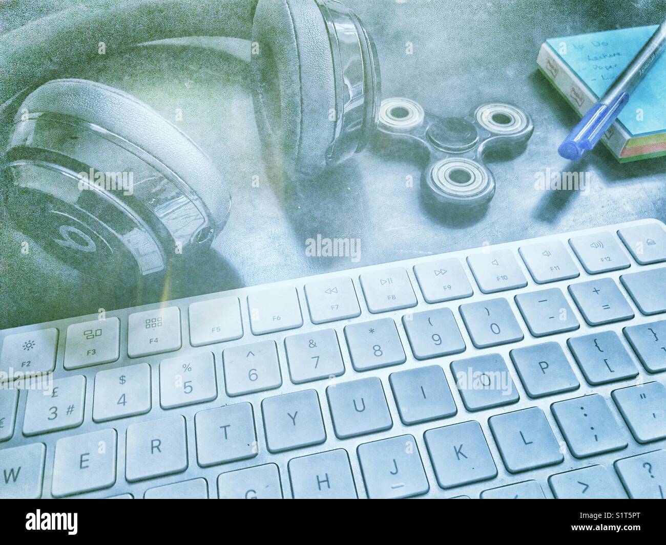 Beat over-ear wireless headphones, computer keyboard, notepad and pen, fidget spinner, on a leather desktop. - Smartphone Captured Stock Image