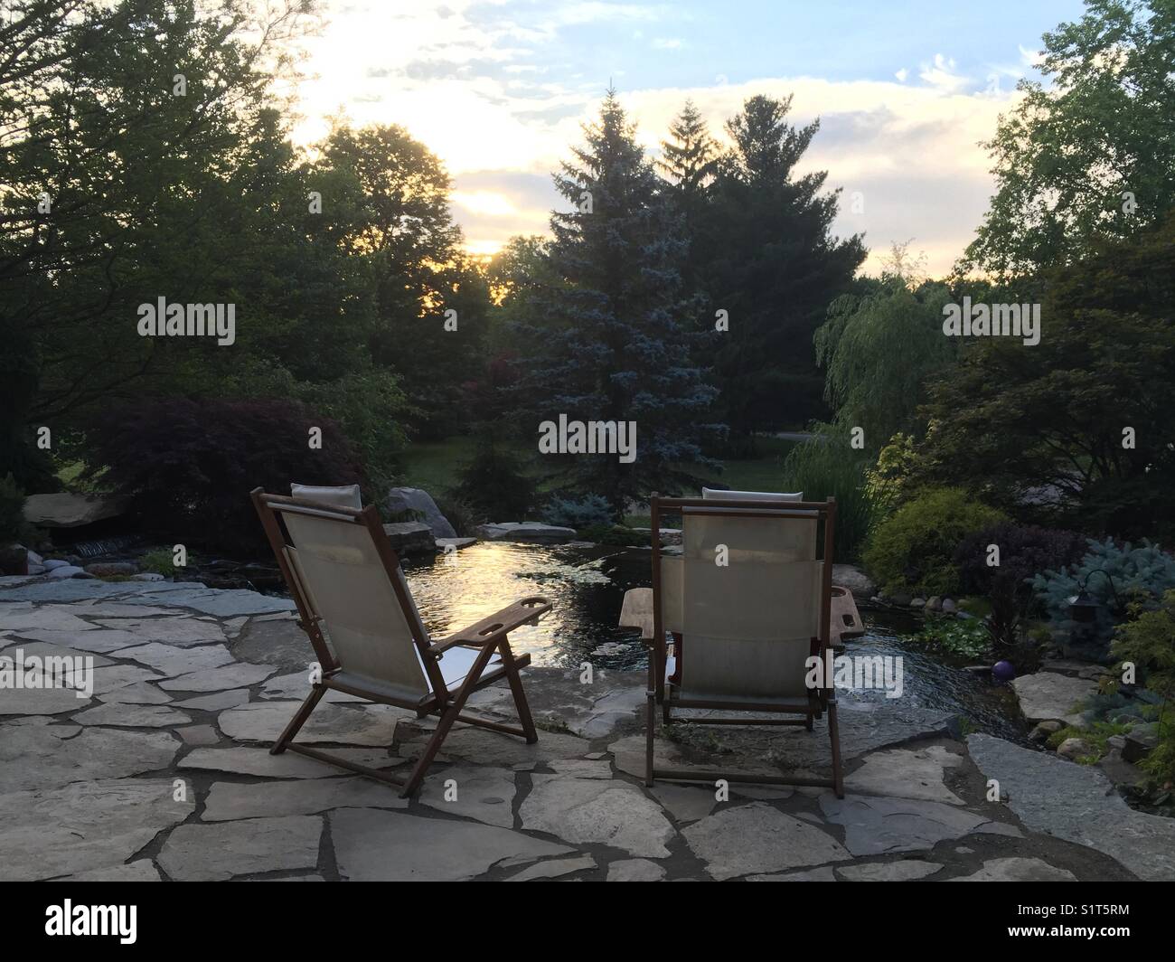 Two outdoor chairs next to pond at sunrise - Smartphone Captured Stock Image