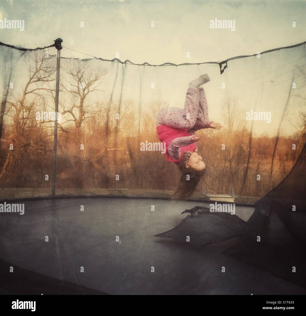 Girl captured in midst of doing flip in the air on a trampoline Stock Photo