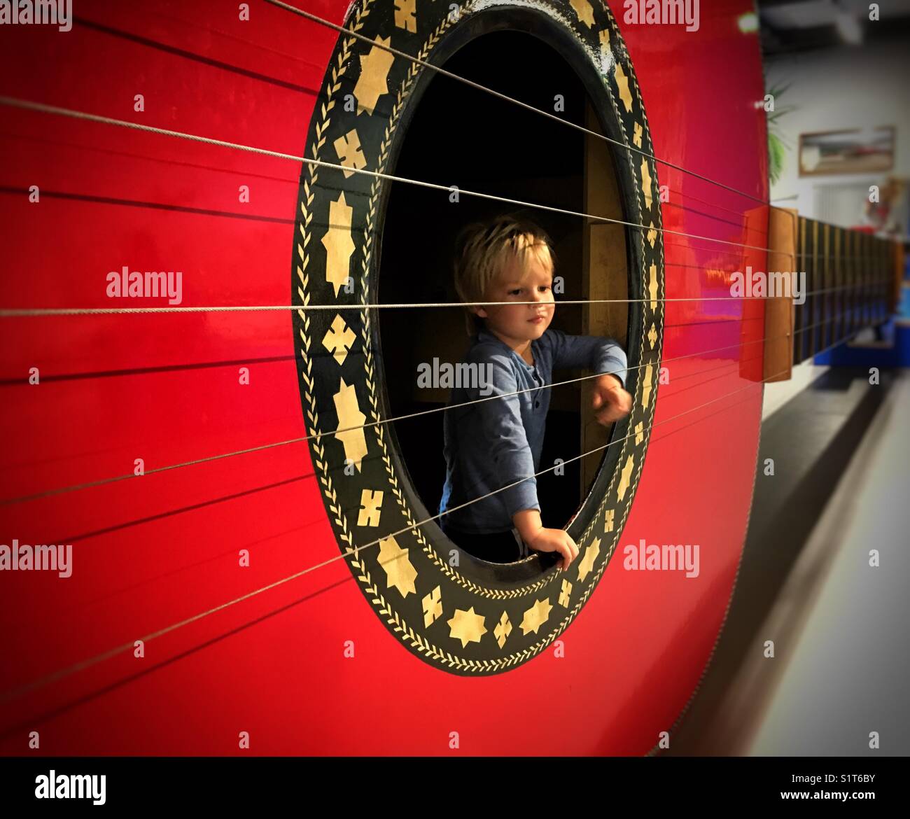Child exploring the giant guitar in Deutsches Museum, Munich. Giant guitar made by ‘The Stradivarium‘: Anthony Dale, Chris Challen, Lucy Coad, Jem Le Livre, Ian Blythe & Julian Thompson. Stock Photo