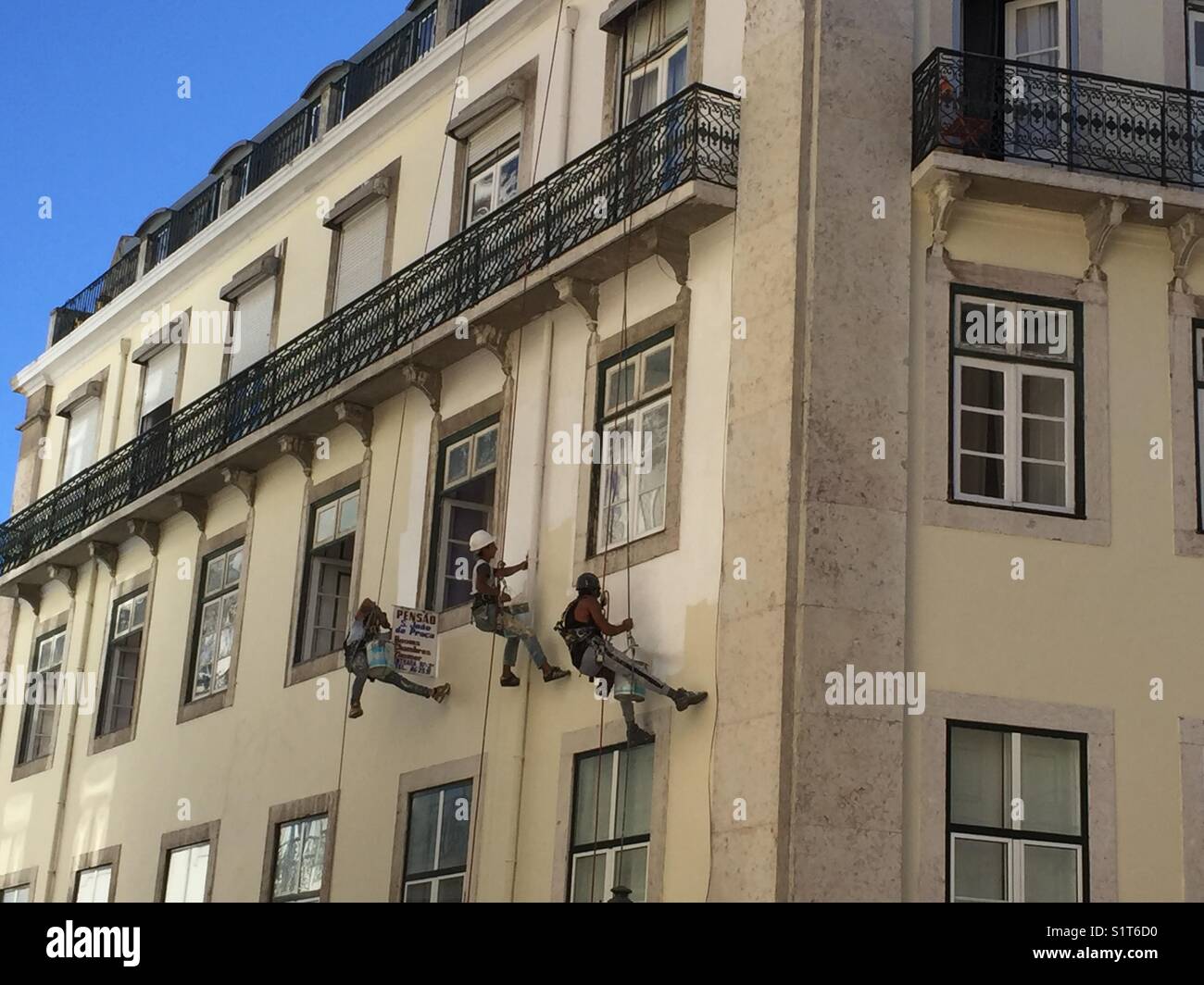 Close up of three men painting a building in Lisbon Stock Photo