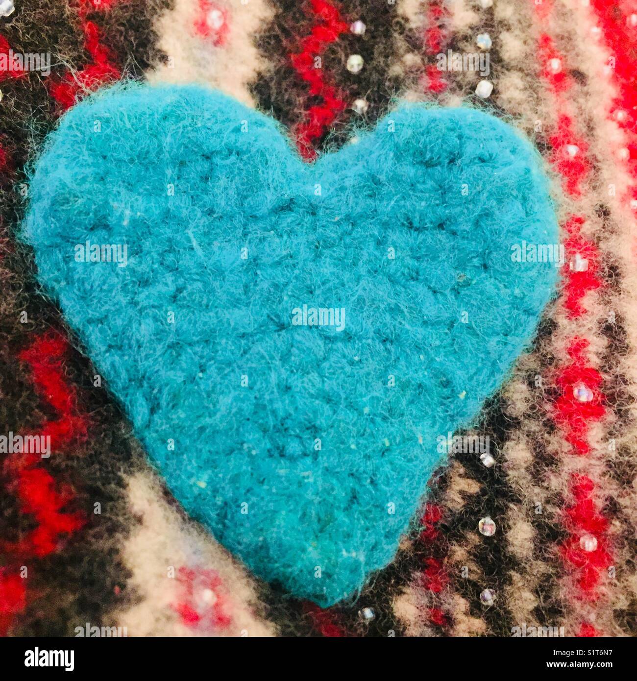 Vibrant teal blue crocheted heart on knitted background Stock Photo