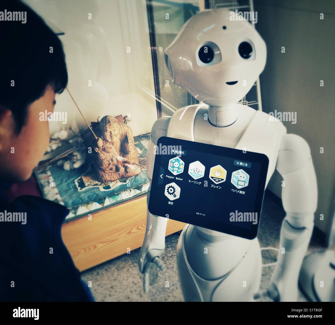 Asian 6 years old boy looking at control panel of interactive robot in Japan Stock Photo