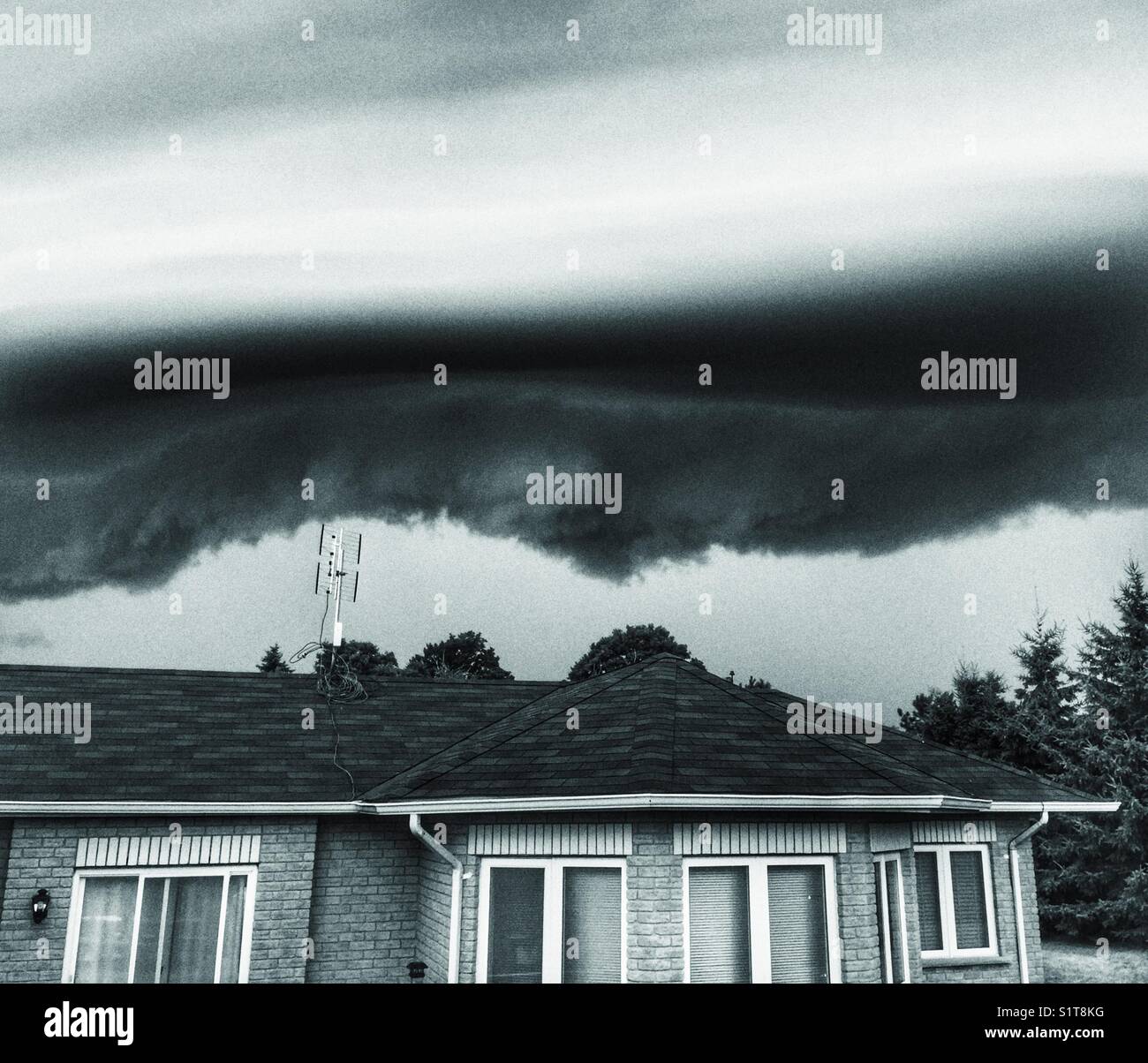 Ominous looking storm with a shelf cloud being viewed above a house in Clarington, Ontario, Canada Stock Photo
